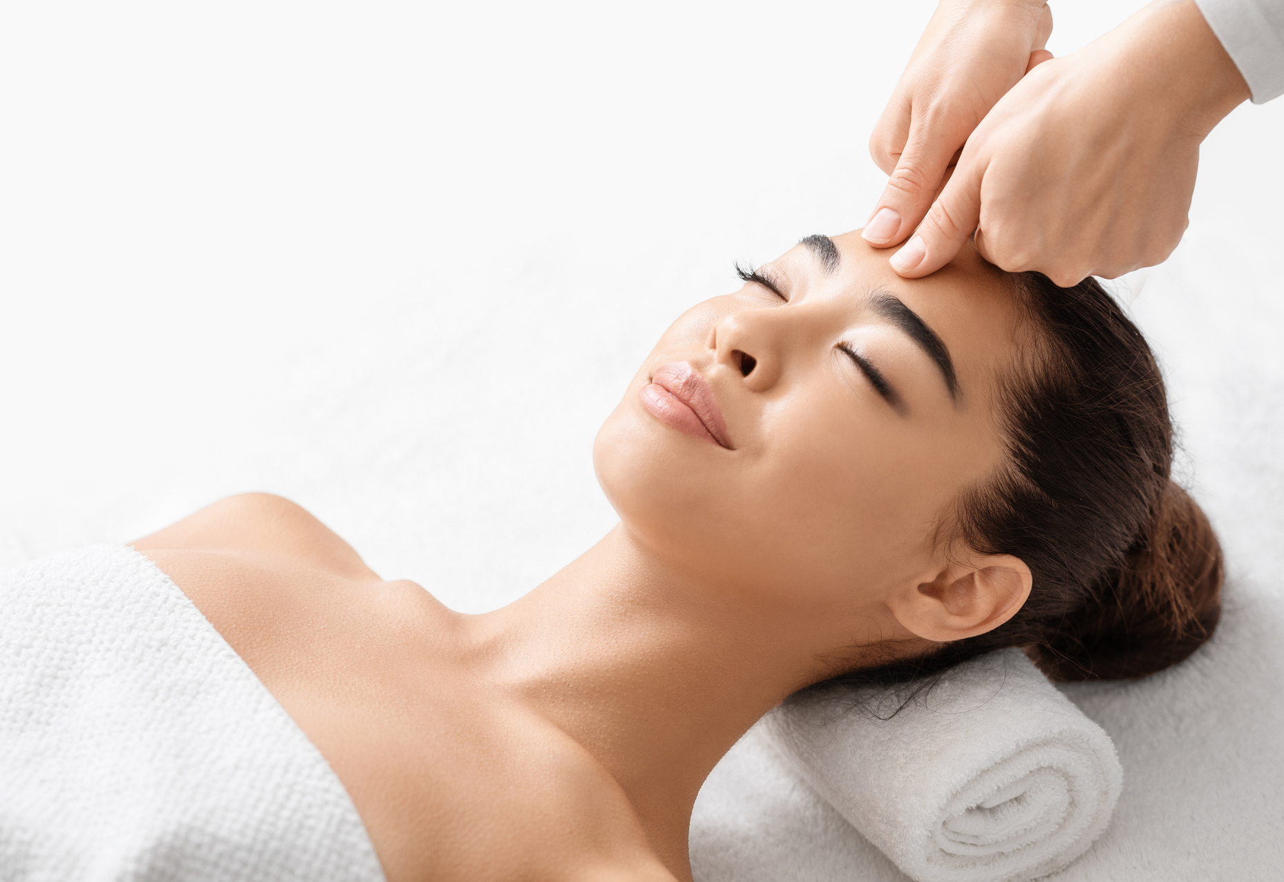 Attractive young korean woman receiving acupressure head massage in spa salon