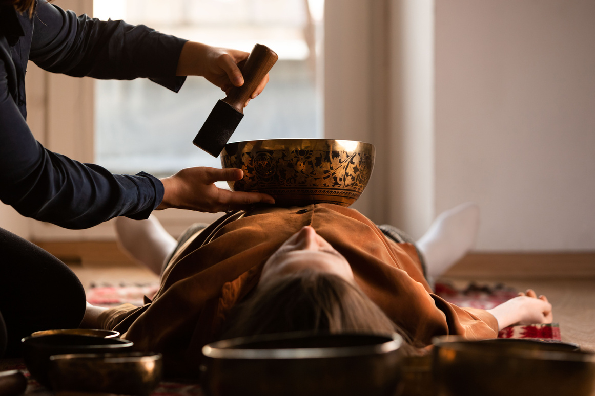 Woman making relaxing massage, meditation, sound therapy with tibetian singing bowls. Stress relief